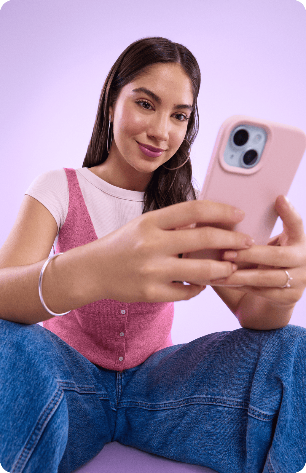 Una persona sonríe mientras sostiene su teléfono morado en la mano